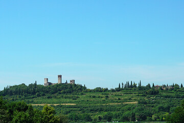 Fototapeta na wymiar Medieval Italian castle built in a valley. Towers of an ancient castle among the vegetation of the countryside.