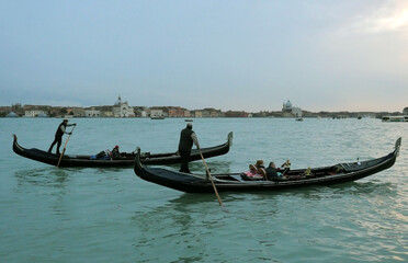 Two gondoliers greet each other as they sail.
Tourists on gondola during sunset. Lifestyle in Venice.