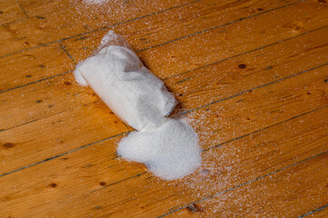 bag of granulated sugar fell to the wooden floor and shattered