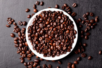 Cup of coffee with beans on table, top view