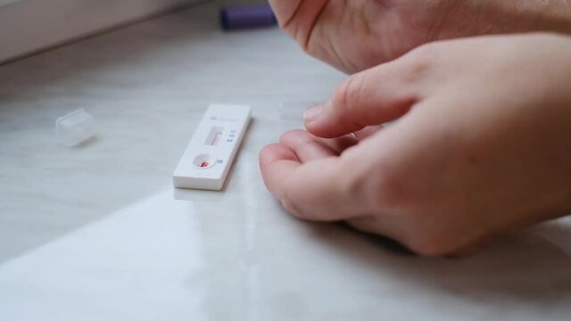 A woman doing a rapid test at home to determine the coronavirus, COVID 19. PatienCovid-19 test kit for the determination of IgM IgG antibodies and immunity in 15 minutes.
