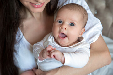 A kid with joyful emotions.. The child yawns in his mother's arms. Mom and beautiful daughter on a white background , lifestyle 