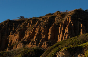 A man standing on top of the El Matador Beach's cliff