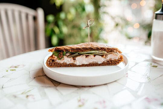 Baguette Sandwich Cut In Half With Turkey Breast, Cheese, Lettuce Leaves On A Plate Close-up