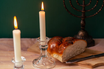 two candles, a menorah and Homemade challah on a wooden table.