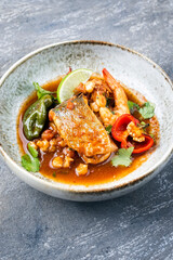 Modern style traditional Mexican seafood pozole soup with fish, king prawns and hominy in a clear sauce served as close-up in design bowl