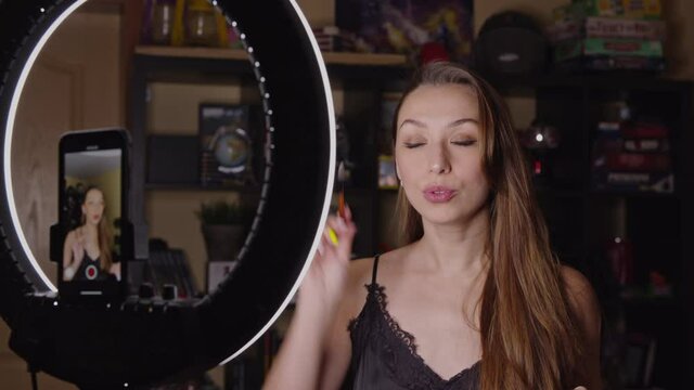 Beauty blogger recording daily makeup routine tutorial on smartphone with selfi ring light. Influencer live streaming, cosmetics product, shares beauty tips and hacks on online webinar classes.