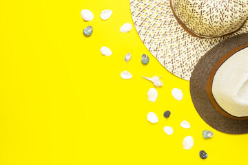 Male and female straw hats and seashells on vivid yellow background. Summer holiday concept.