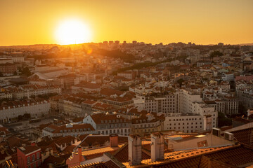 Fototapeta premium Beautiful yellow sunset in Lisbon, Portugal. Sun rays over red rooftops. Traveling seatination. Romantic vacation in beautiful city.