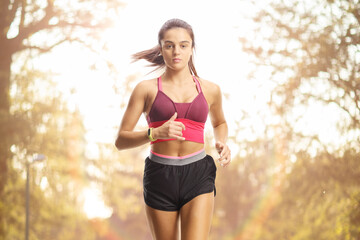 Fototapeta premium Young female in sportswear running towards camera
