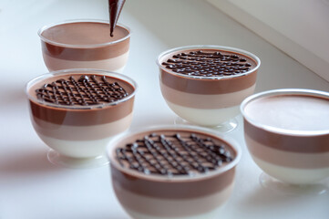 Chocolate covered mousse in plastic jars. Dessert three chocolate, white, milk and dark. Decorating with piping bag. Pouring melted chocolate.