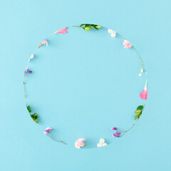 Creative spring layout made of colorful flowers, leaves and pearls on pastel blue background with copy space. Minimal nature concept. Flat lay.