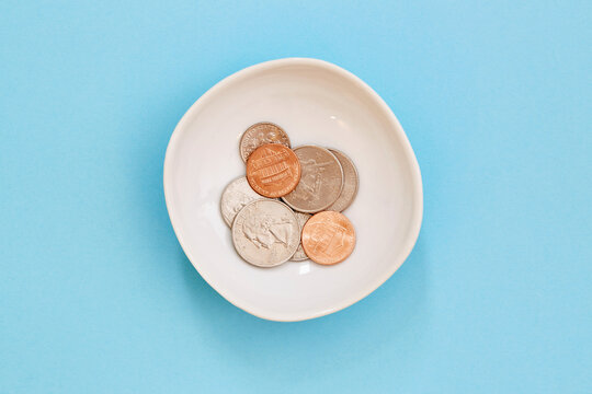 Coins in bowl on blue background