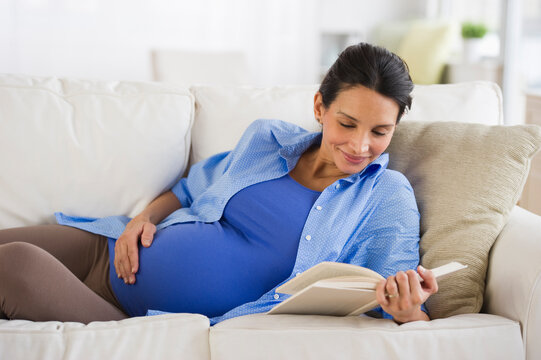 Pregnant woman reading on couch
