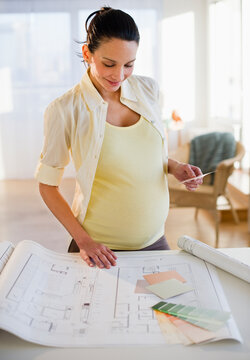 Pregnant woman looking at house plans