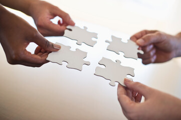Four hands holding puzzle pieces