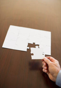 Hand putting last puzzle piece in puzzle