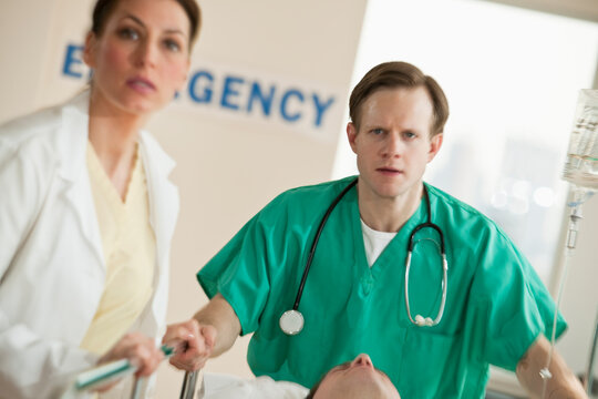Healthcare workers pushing gurney in emergency room
