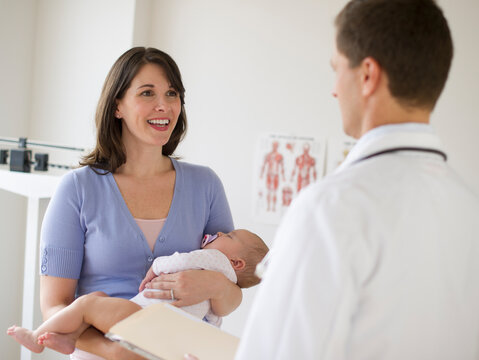 Woman holding baby while talking to doctor