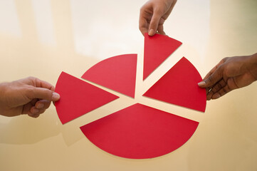 Hands dividing pieces of pie chart