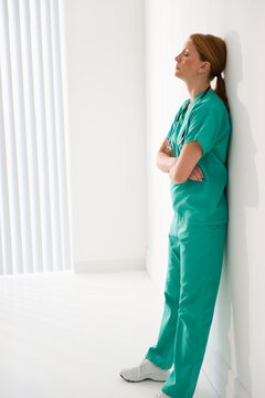 Tired healthcare worker leaning against wall