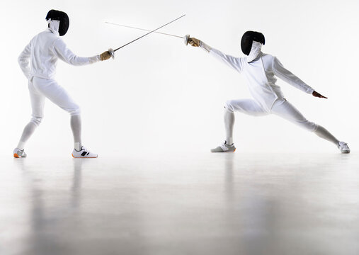 Studio shot of fencers in attacking lunge