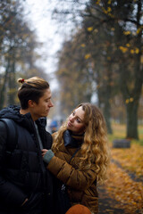 Fototapeta premium young couple looks at each other tenderly. young loving couple hugs in the park with yellow leaves on the background. 