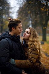 Fototapeta premium the girl hugs the man and looks passionately into his eyes. young couple in love hugs in the autumn park. 