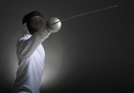 Studio portrait of fencer holding fencing foil