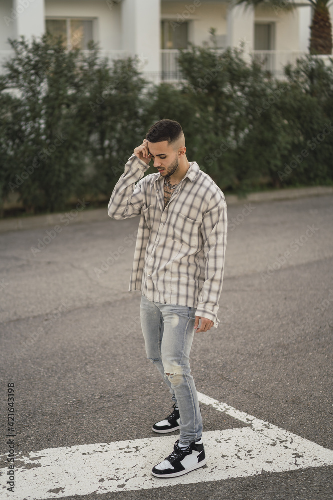 Sticker vertical shot of a handsome caucasian spanish man with tattoos posing outdoors