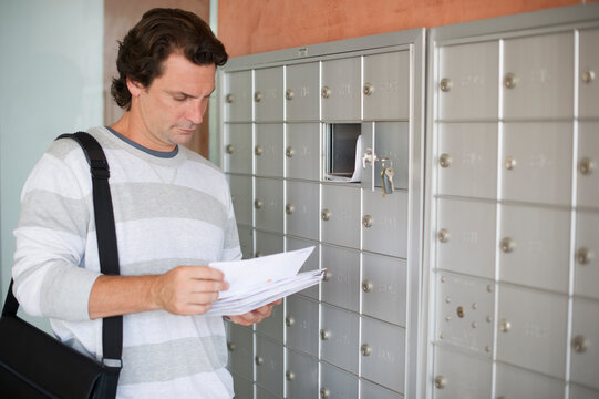 Man standing next to mailboxes and checking post