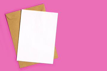 Obraz na płótnie Canvas Brown envelope with white paper on pink background.