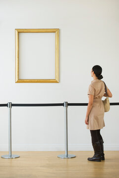 Woman looking at blank picture frame in art gallery