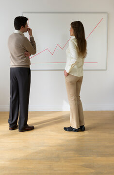 USA, New Jersey, Jersey City, Businessman and woman observing line graph