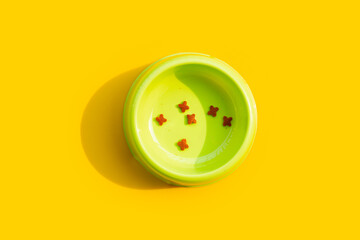 Dry cat food  in green bowl on yellow background.