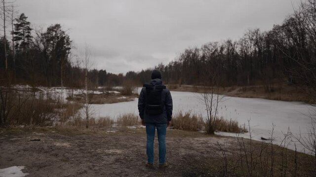 Lonely sad man, standing with his back and looking at frozen lake inforest. Depression, bad mood and suicidal thoughts. I need psychological help. Winter nature and male thinks about life