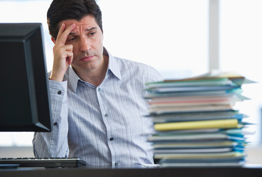 USA, New Jersey, Jersey City, Businessman staring at stacked paperwork on desk