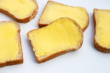 Bread slices with butter on white background.