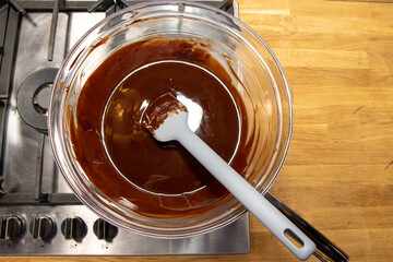 A glass bowl of melted chocolate being melted on a stove in a kitchen