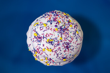 Easter holidays isolated sweet bread, paska decorated with sugar icing on blue background top view. Orthodox traditional colorful handmade kulich with topping