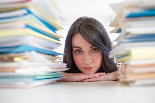 Young woman looking at stack of documents at desk