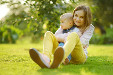 Cute big sister admiring her baby brother. Adorable teenage girl holding her new baby boy brother....