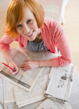 Young woman circling ads in newspaper
