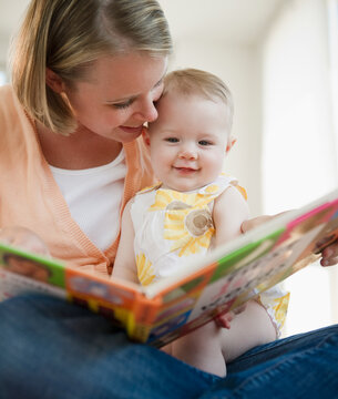 Mother reading book to her baby daughter