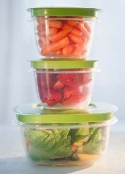 Carrots, strawberries and salad in plastic containers, studio shot