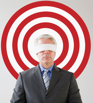 Blindfolded man standing in front of bull's eye