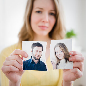 Woman holding torn photograph