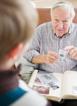 Grandfather and grandson (8-9) watching family photos