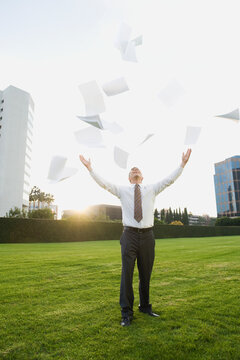 Businessman throwing papers in air