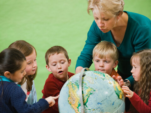 Teacher showing globe to kindergarten students